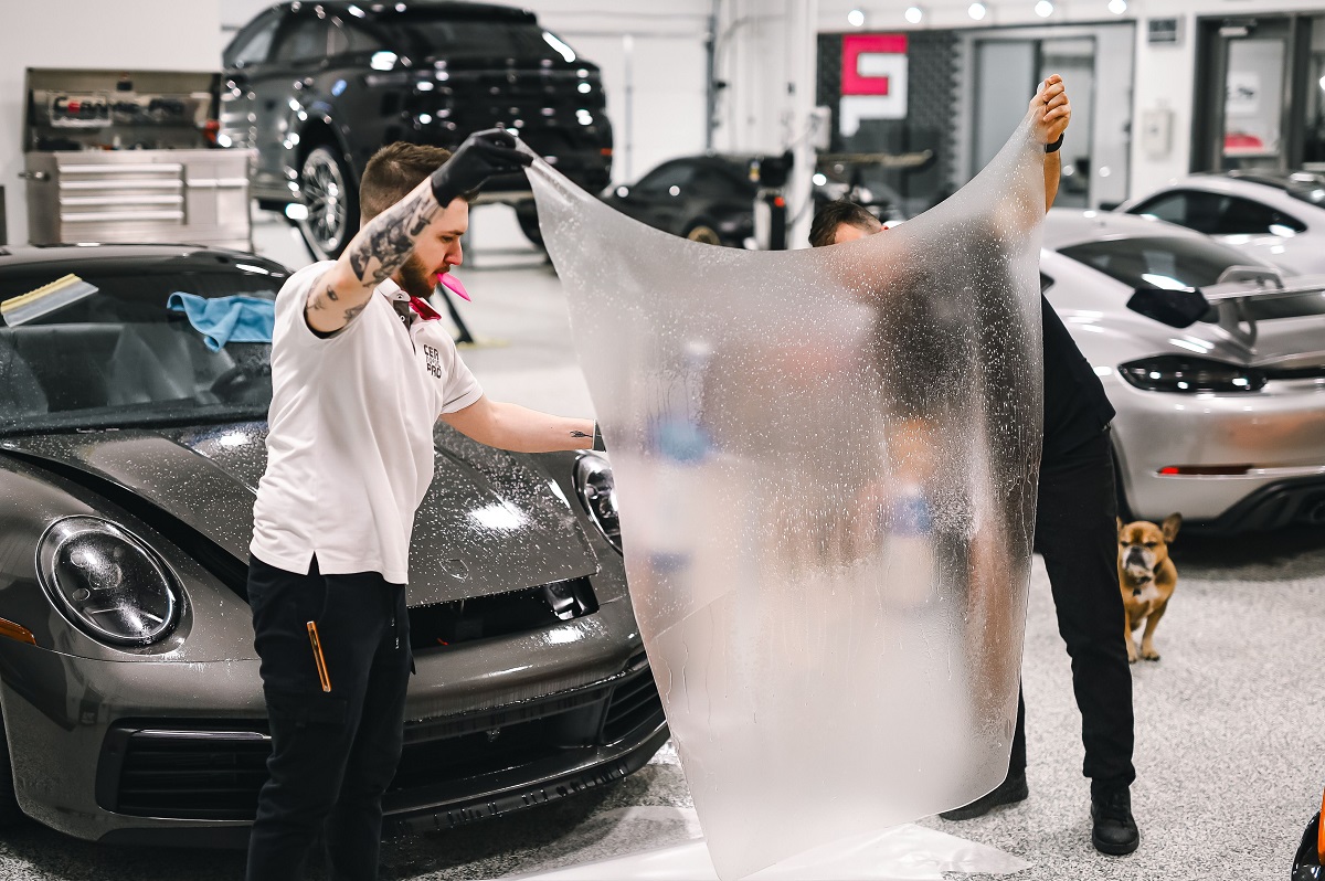 two men applying protective film to a black car
